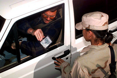 Airman Mary Ann Hubany, a security forces specialist, checks a driver's military identification card for positive identification before allowing the vehicle to enter the U.S. military compound at an operating base in Southwest Asia on February 23, 1998. (DoD photo)