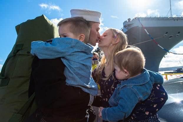 Machinist's Mate 2nd Class Skyler Record (left), from Salt Lake City, greets his spouse with the traditional first kiss after returning from deployment on the USS Nimitz, Mar. 7, 2021. Photo by Sarah Christoph