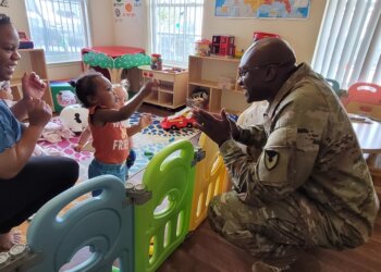 Command Sgt. Maj. Shelly Jenkins, Fort Drum garrison senior enlisted adviser, entertains a toddler during a routine inspection of a Family Child Care home. (Photo by Mike Strasser, Fort Drum Garrison Public Affairs)