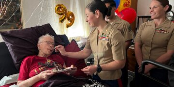 Marine Corps Maj. Shannon Potts, a manpower officer assigned to Headquarters Company, 23rd Marine Regiment, 4th Marine Division helps retired Marine Corps Cpl. Lou 'Mama Lou' Keller eat her birthday cake during Mama Lou's 99th birthday celebration, March 30, 2024, in San Jose, California. Image courtesy of 23rd Marines