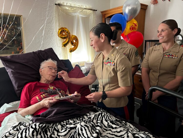 Marine Corps Maj. Shannon Potts, a manpower officer assigned to Headquarters Company, 23rd Marine Regiment, 4th Marine Division helps retired Marine Corps Cpl. Lou 'Mama Lou' Keller eat her birthday cake during Mama Lou's 99th birthday celebration, March 30, 2024, in San Jose, California. Image courtesy of 23rd Marines