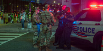U.S. Army 2nd Lt. Harry Siegel and Sgt. 1st Class Nikolay Bashko talk with Metropolitan Police Department officers near Nationals Park, Aug. 19, 2025. The D.C. National Guard is uniquely commanded by the President of the United States through the Secretary of Defense. Guard members were activated under the Joint Task Force–District of Columbia as part of the D.C. Safe and Beautiful Task Force to support District and federal partners in safeguarding property and ensuring the functions of government. (U.S. Army Photo by Spc. Carrol Walter Hughes IV)
