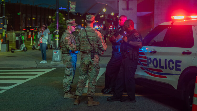 U.S. Army 2nd Lt. Harry Siegel and Sgt. 1st Class Nikolay Bashko talk with Metropolitan Police Department officers near Nationals Park, Aug. 19, 2025. The D.C. National Guard is uniquely commanded by the President of the United States through the Secretary of Defense. Guard members were activated under the Joint Task Force–District of Columbia as part of the D.C. Safe and Beautiful Task Force to support District and federal partners in safeguarding property and ensuring the functions of government. (U.S. Army Photo by Spc. Carrol Walter Hughes IV)