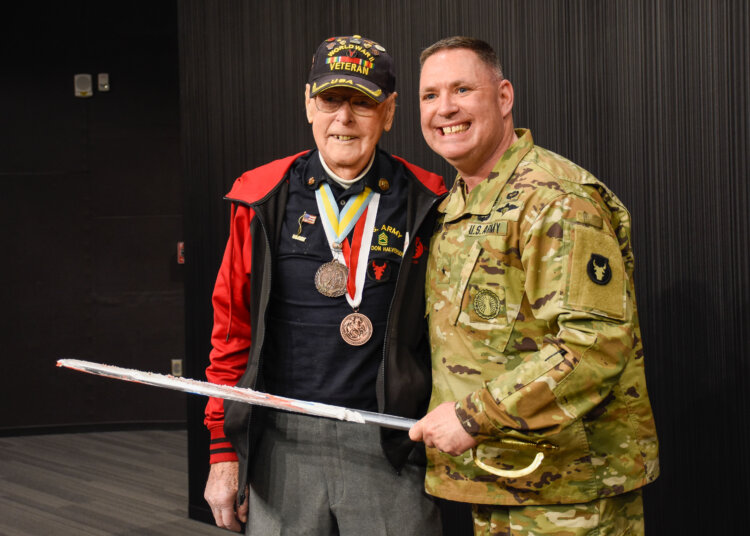 103-year-old veteran Don Halverson cuts the cake with help from Brig, Gen. Joseph Sharkey