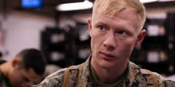 U.S. Marine Corps Cpl. Nathaniel Hill speaks to another Marine during a gear issue at Fort Devens, Massachusetts, Dec. 14, 2025. Hill is a rifleman with Charlie Company, 1st Battalion, 25th Marine Regiment. Marines took part in this event as an ongoing effort to prepare and maintain readiness for upcoming training and operations. (U.S. Marine Corps photo by Lance Cpl. Priscilla Flores)
