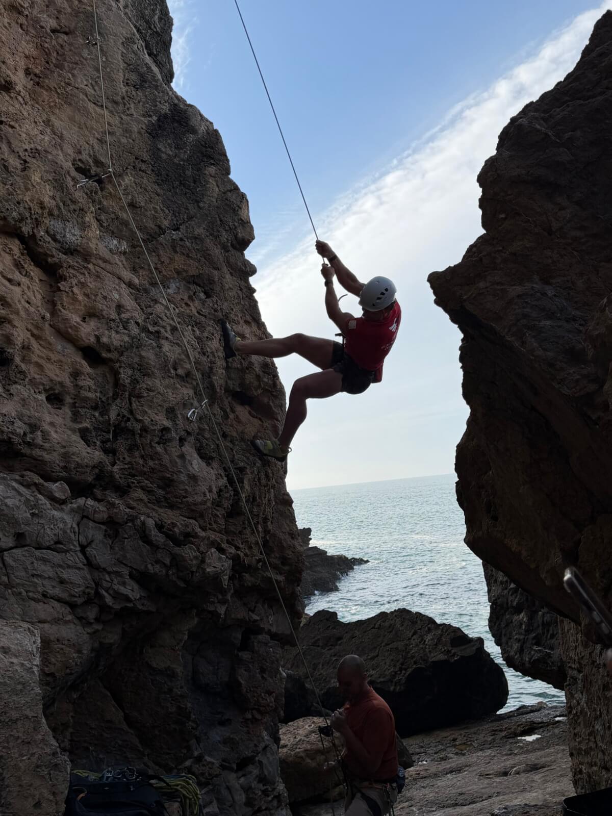 Enjoying nature, John Forshtay uses a rope to climb a rock in Cascais, Portugal.