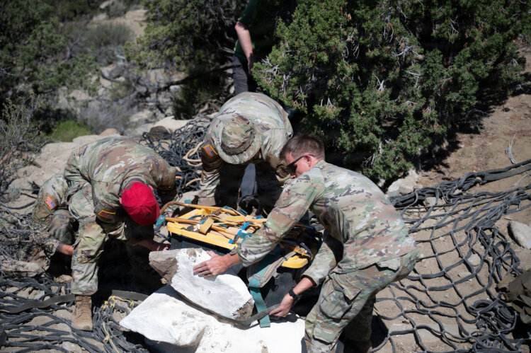 Parachute riggers assigned to 19th Special Forces Group (Airborne) stack an encased duck-billed dinosaur skeleton and tools to prepare for an aerial hoist near Escalante National Monument, June 12, 2026. Photo by Staff Sgt. Ian Tracy